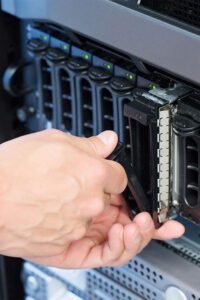 IT Support technician changing hard drive in server close up vertical